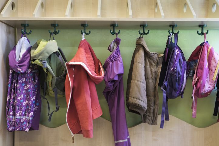 Taschen und Kleidung hängen an einer Garderobe