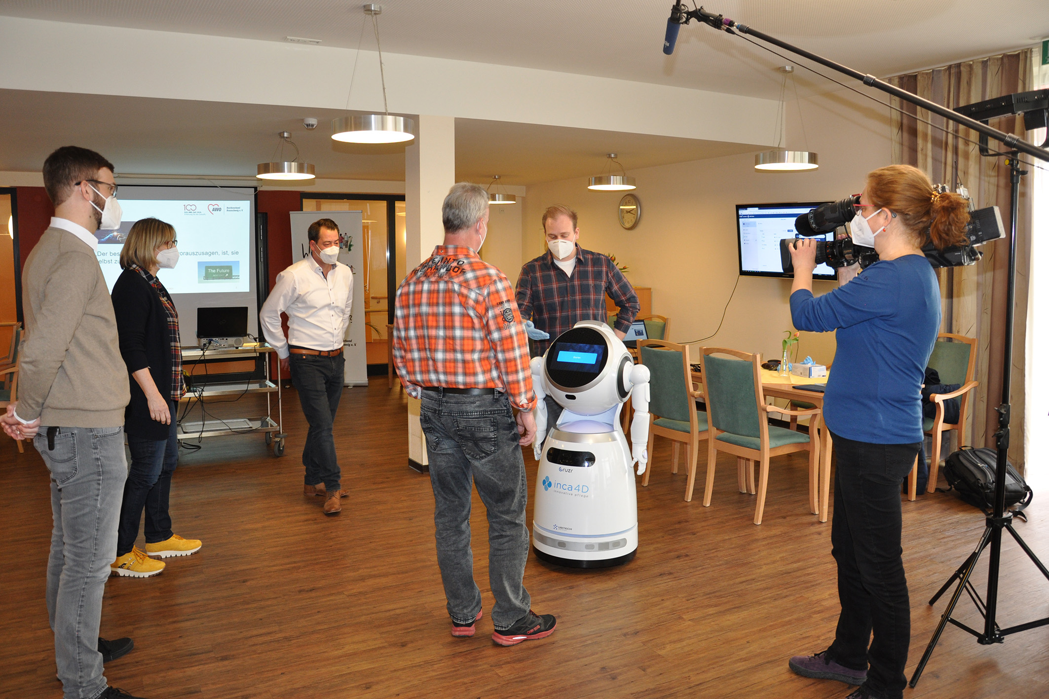 Der NDR filmte in einem Workshop, in denen Gerrit Lose von der Ostfalia (hinter dem Roboter) den Teilnehmer*innen erläutert, was Cruzr alles kann.