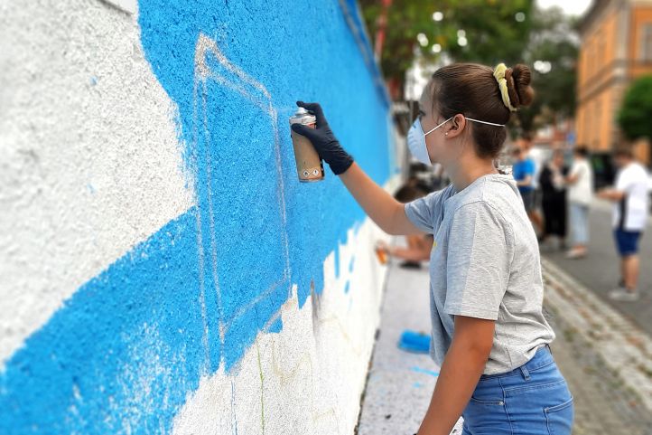 Mädchen sprüht ein Bild an eine Mauer