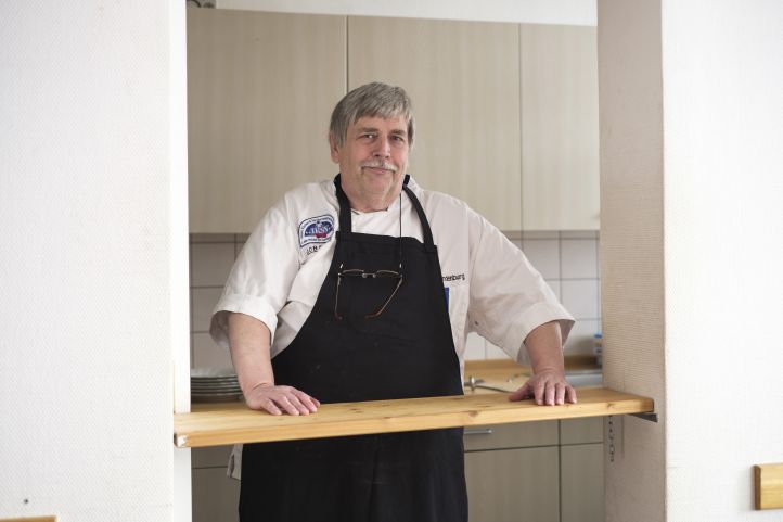 Mindestlohn - Mann mit Kittelchürze an Theke