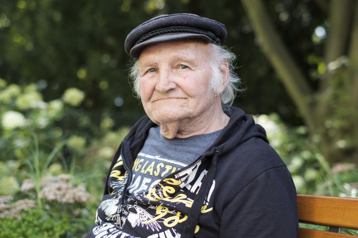 Mann mit Schirmmütze sitzt auf einer Bank