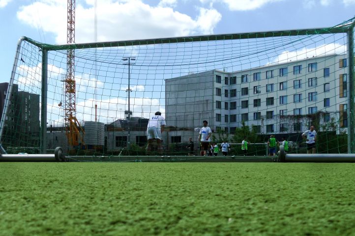 Ein Fußballtor und Menschen im Hintergrund mit Plattenbauten