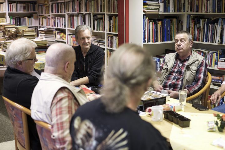 Gruppe Männer sitzt um Bücherregal
