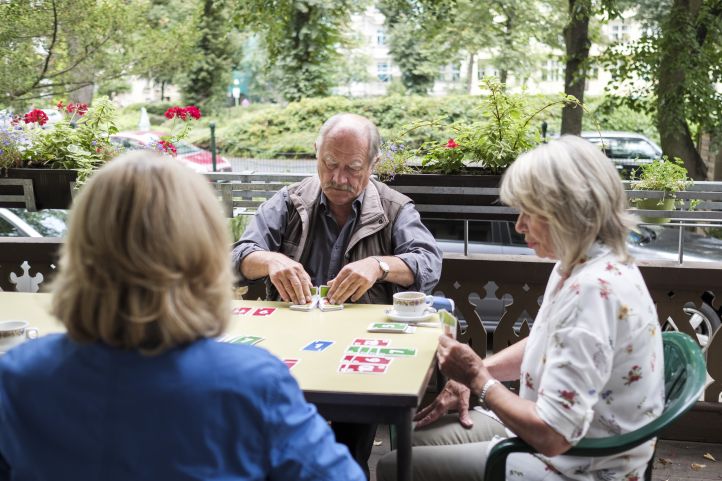 Man und Frauen spielen Karten
