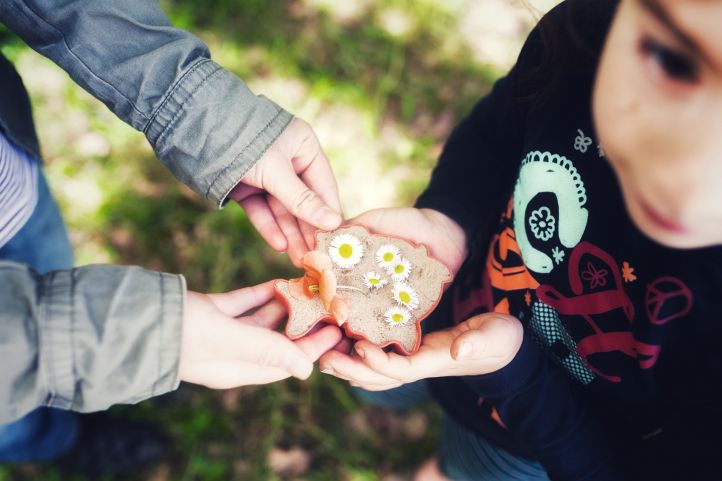 Zwei Kinder Mädchen halten eine Form ein Förmchen mit Sand gefüllt, in dem Blumen liegen