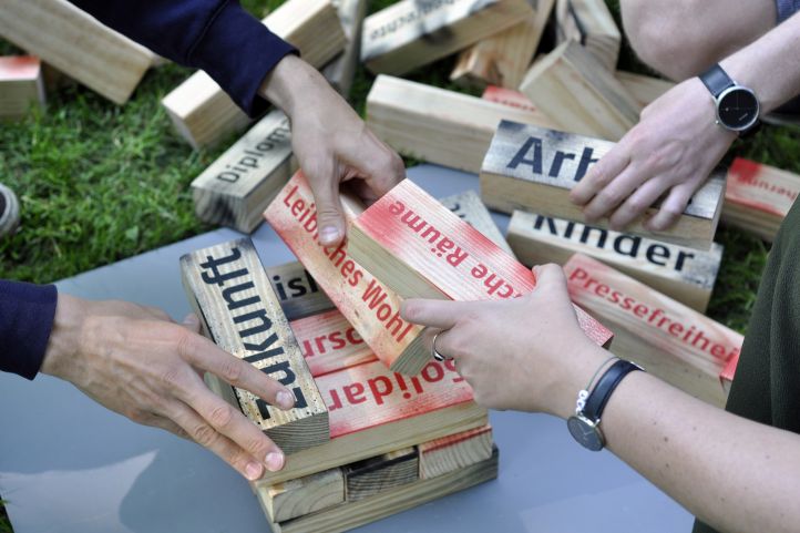 Hände halten Holzklötze in der Hand und bauen sie zu einem Turm. 