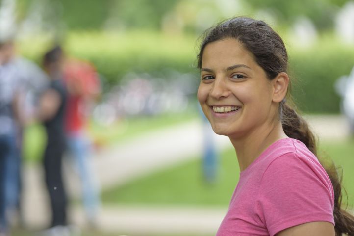 eine Frau mit Zopf lacht in die Kamera