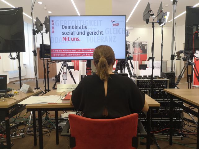 Impressionen von der digitalen Bundeskonferenz 2021, Frau in Rückenansicht vor Monitor mit dem Konferenzmotto