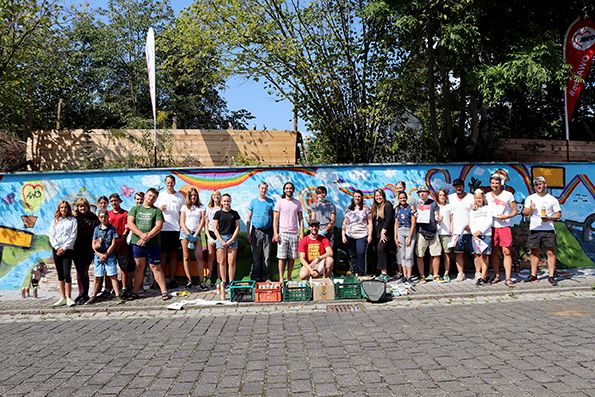 Viele Menschen posieren vor einer bunten Wand