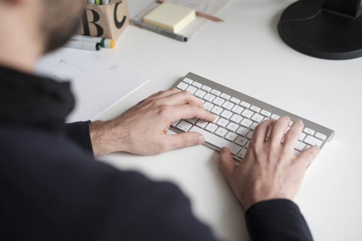 Hände eines Mannes, die auf einer schnurlosen Tastatur tippen